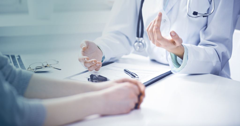 a doctor talking to a person while sitting at a table