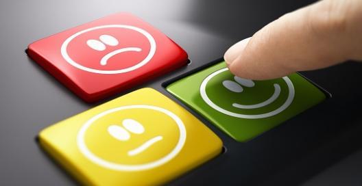 Stock photo of a finger touching keyboard buttons indicating happy, sad or inbetween.