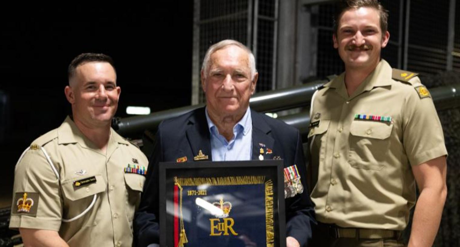 Older man in civilian clothes flanked by two younger men in Army uniform