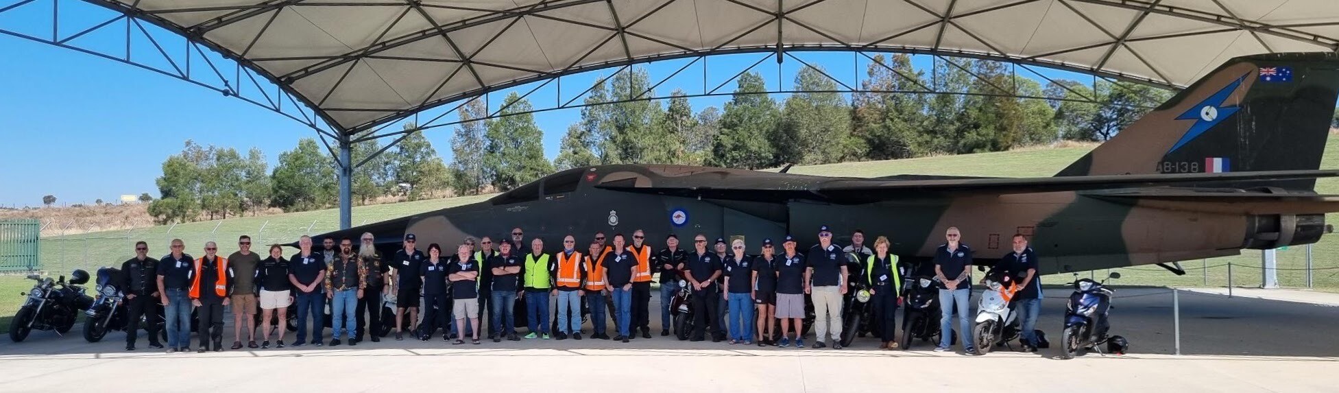 About 40 men and women posing for photo in front of F-111 aircraft.