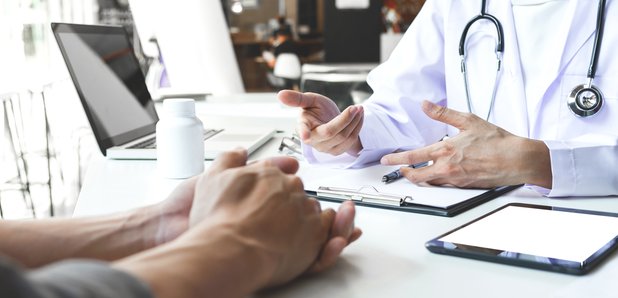 Close up of GP and patient hands resting on table.