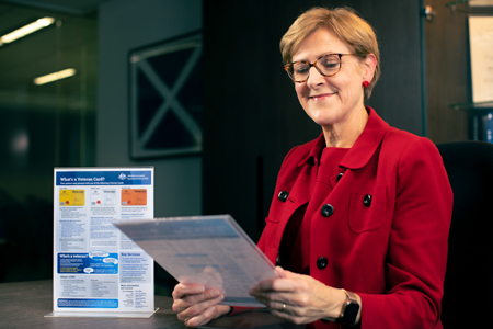 Lady looking at the 'What's a Veteran Card' guide which is displayed in an acrylic holder.
