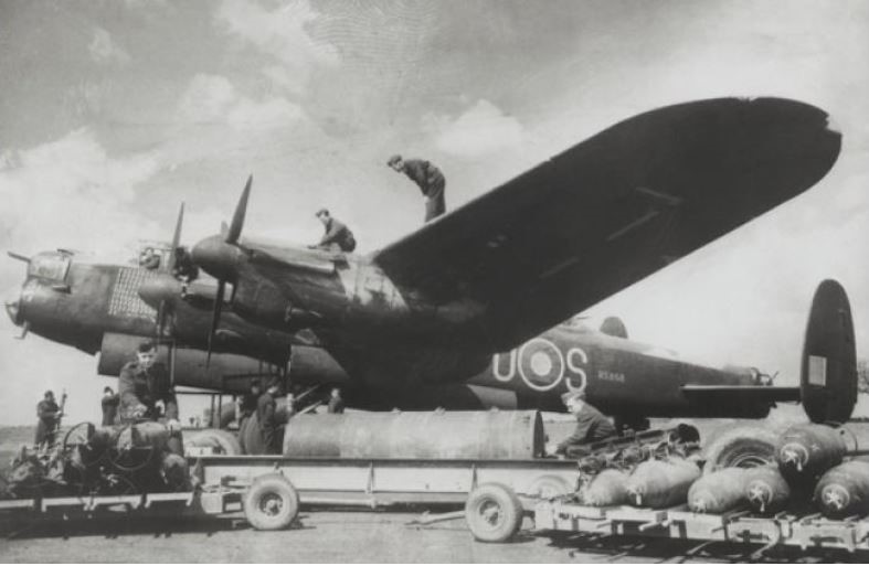 Lancaster bomber with bombs next to it and crew on wings