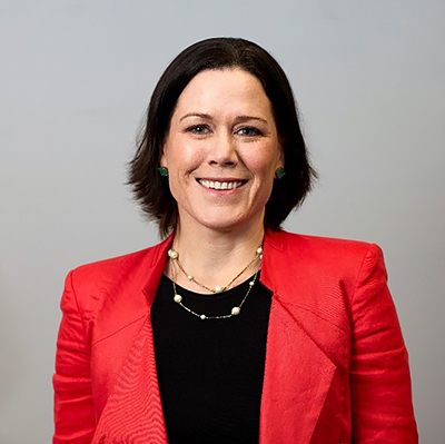 Photograph of Alison Frame smiling at the camera. She is wearing black and red clothing.