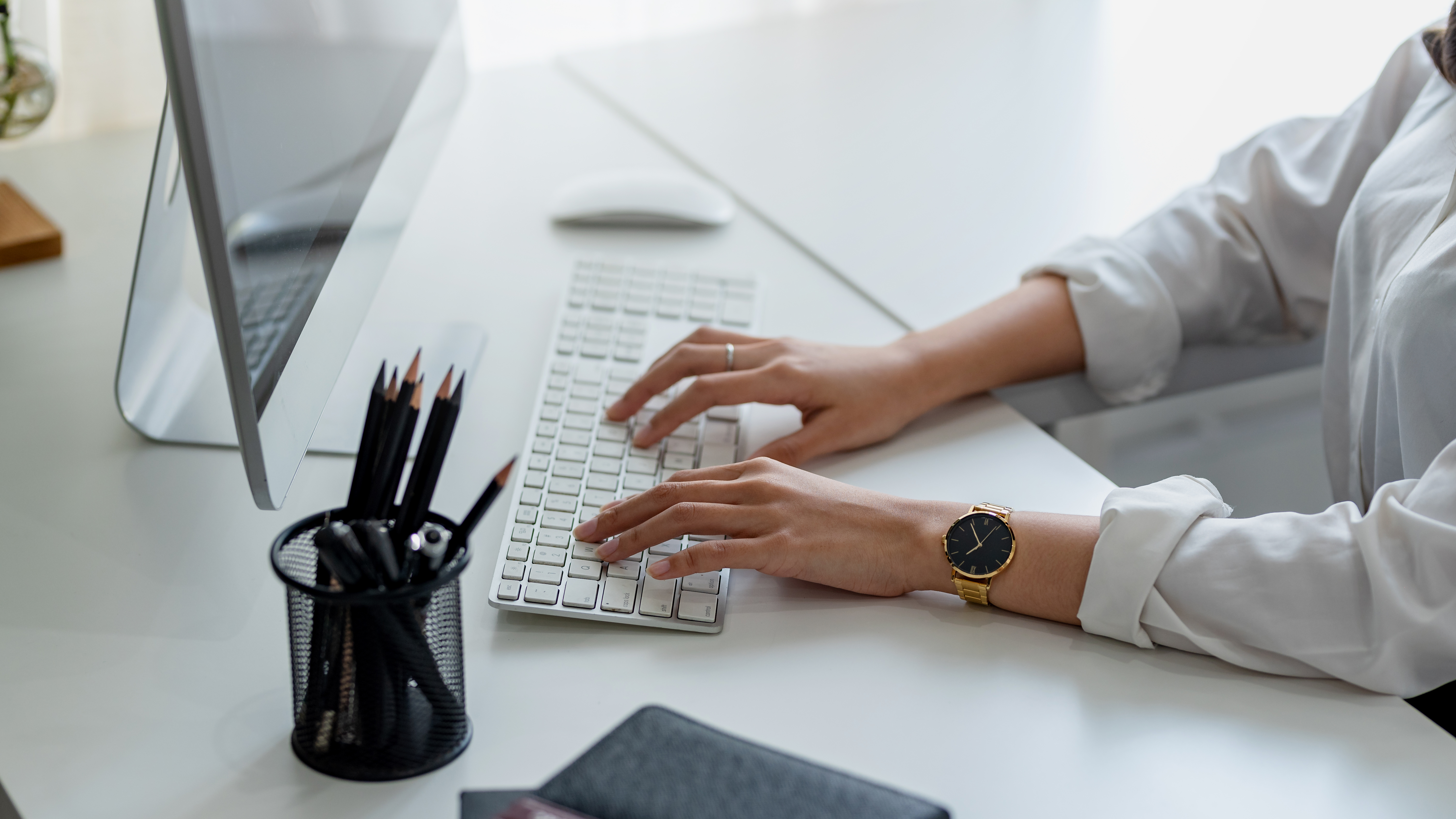 female hand typing on keyboard on a desk in an office