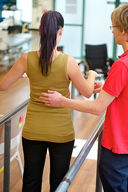 Rehabilitation session with a lady being assisted with walking