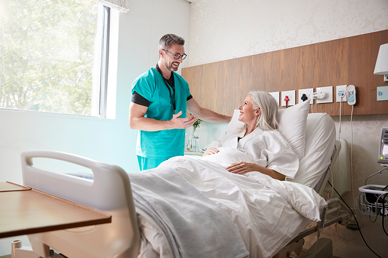 Surgeon Visiting And Talking With Mature Female Patient In Hospital Bed