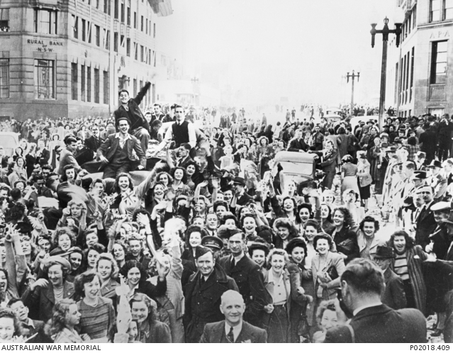 Crowds of civilians and soldiers fill a Sydney city street celebrating VP day.