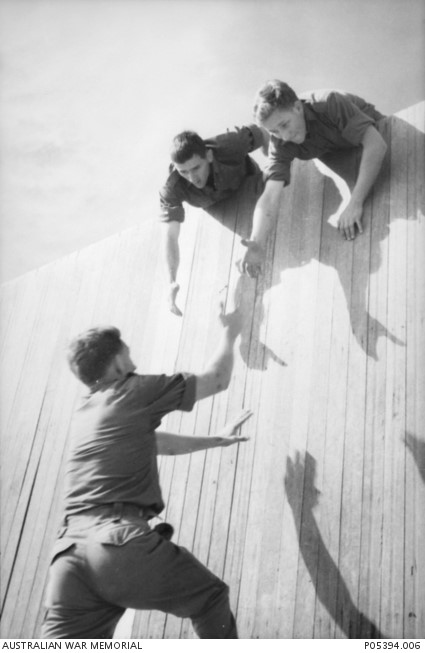 National Servicemen tackle the high wall as part of an obstacle course before active service in Vietnam (AWM P05394.006)