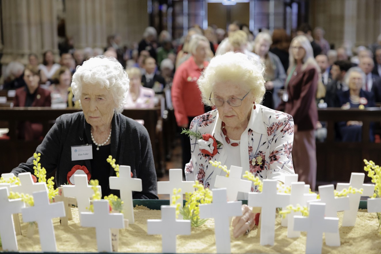 Two widows from the Families of Veterans Guild in front of crosses at its Filed of Remembrance