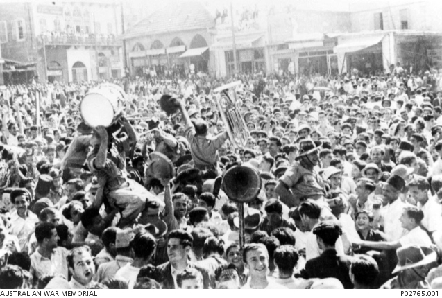 Crowds of people, soldiers and civilians, celebrate in the street on VE Day (Victory Europe).