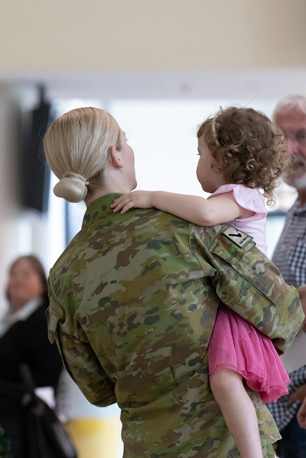 Military mother holding toddler daughter