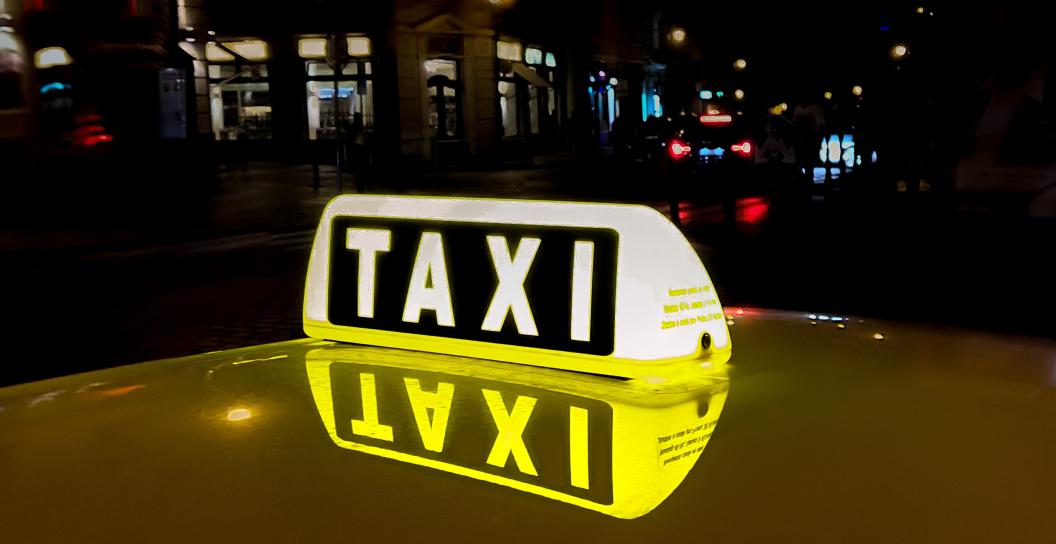 Taxi sign on top of taxi at night