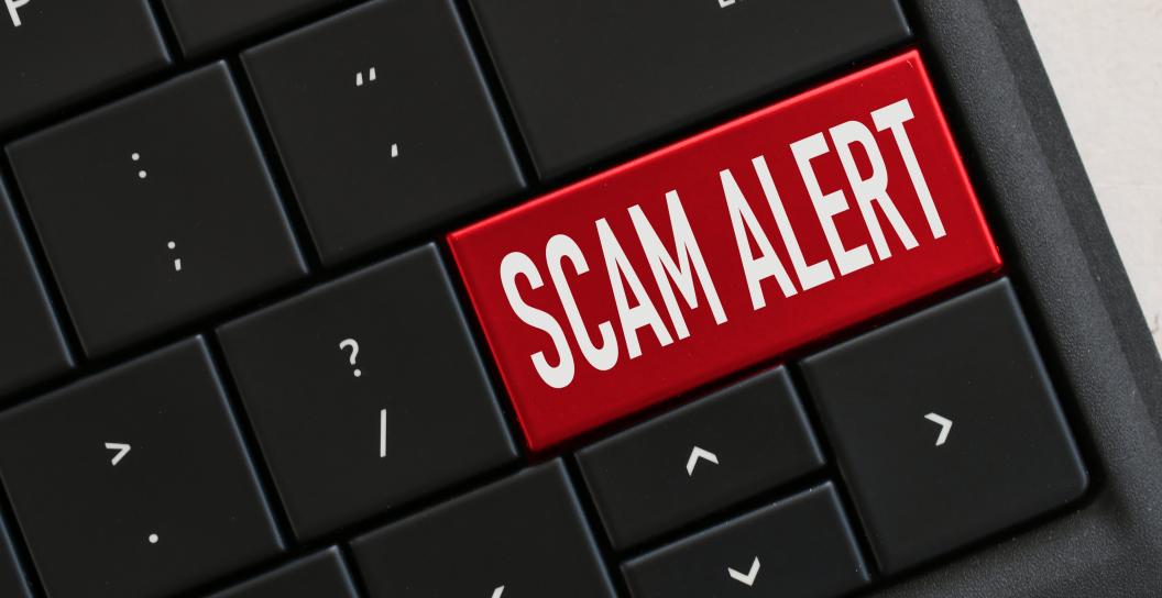 Computer keyboard with red key that says scam alert