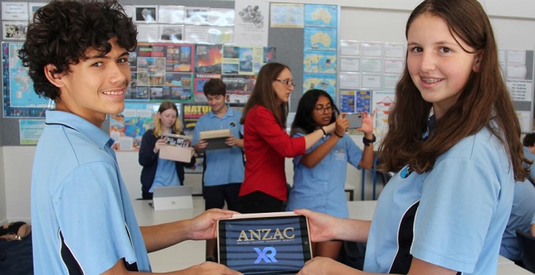 Two school kids hold ipad with Anzac XR on the screen