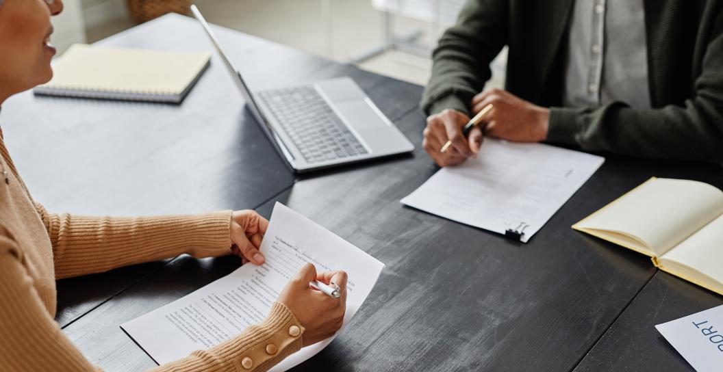 Two people at a desk looking at forms.
