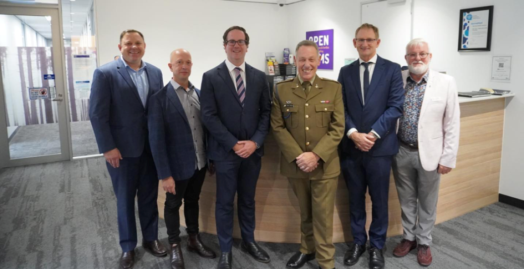 Group of six people smiling and lined up in office foyer