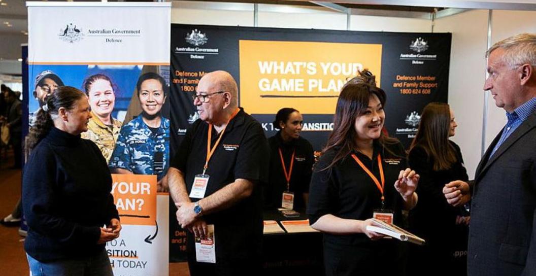Two or three people in black T-shirts talking to people in civilian clothes at a function centre
