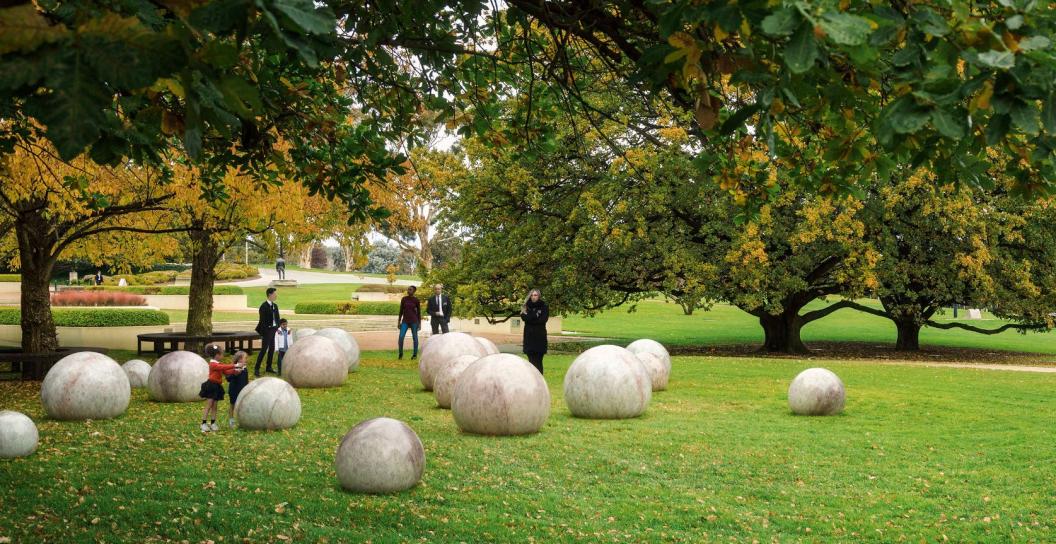 A series of large marble globules scattered around grass