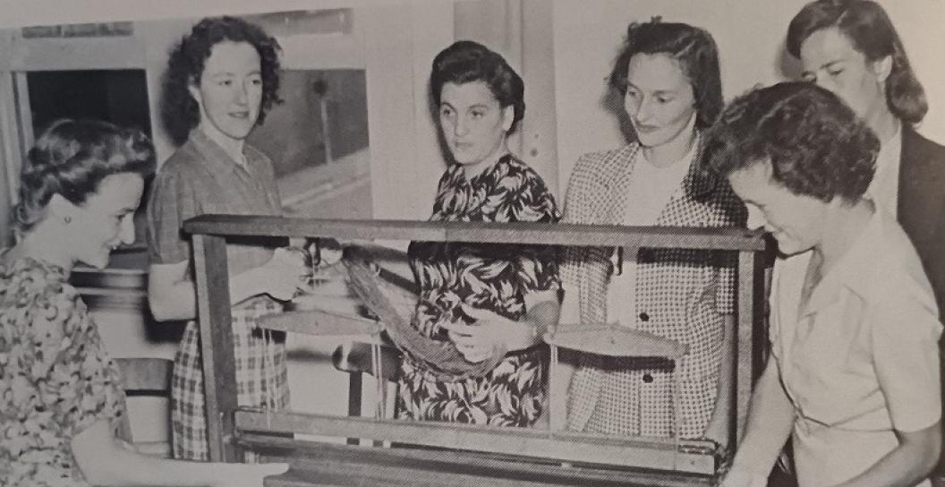 Six women gathered round a loom