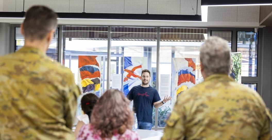 A man addressing a room of civilians and soldiers