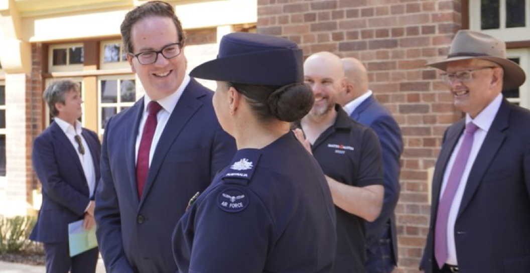 Man talking to woman wearing RAAF uniform; other people in background