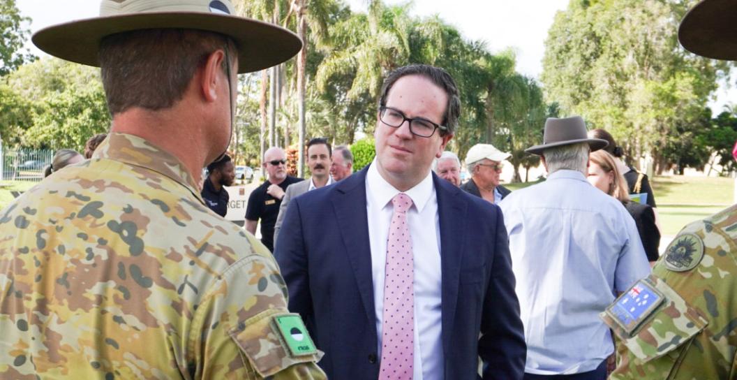 Man in suit talking to soldier in uniform with his back to camera.