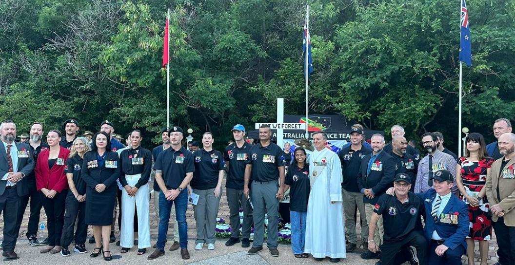 About thirty people standing in front of Australian and Timor-Leste flags at a memorial