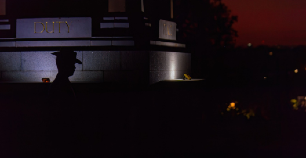 A silhouetted soldier at dawn at a memorial, with the words duty and peace inscribed on the memorial, highlighted