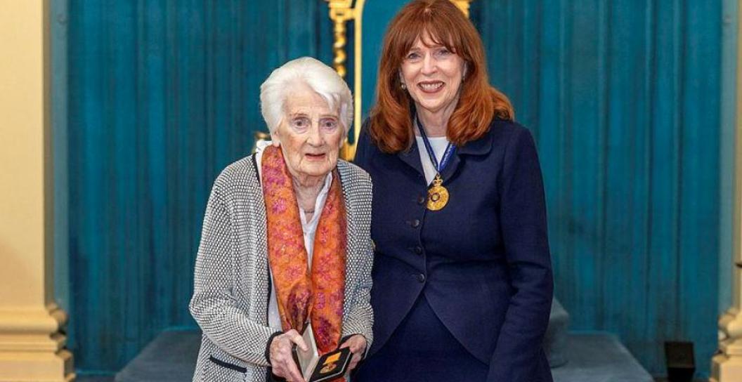 Middle-aged woman poses with elderly woman holding a medal