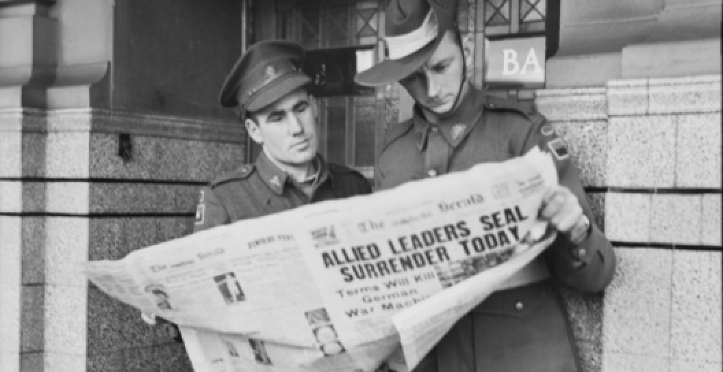 TWO MOTOR TRANSPORT DRIVERS ON VE DAY, READING THE NEWS OF VICTORY IN EUROPE OUTSIDE THE QUEENSBRIDGE HOTEL,