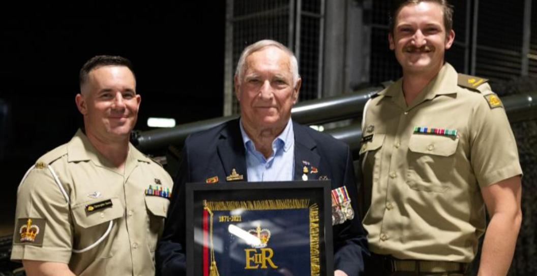 Older man in civilian clothes flanked by two younger men in Army uniform