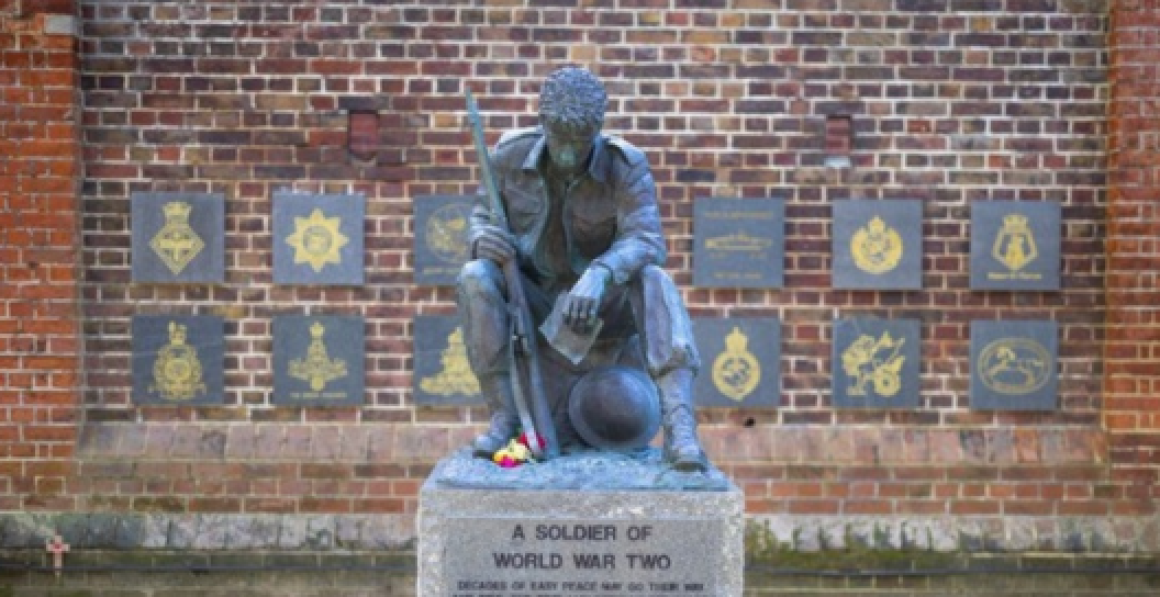 A statue of a World War Two soldier sitting reading a letter