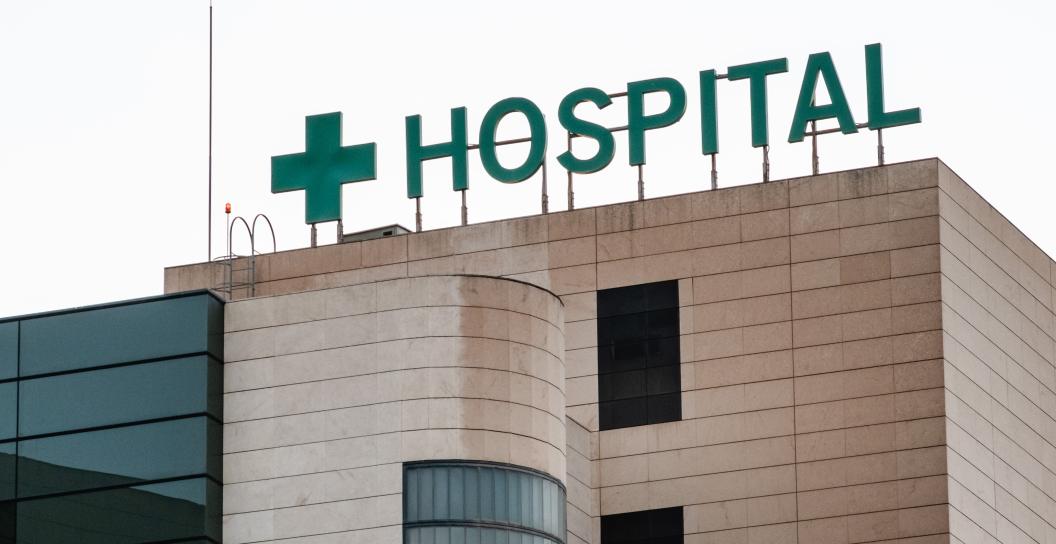 Top of building with green hospital sign and cross