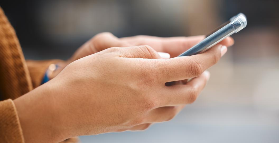 A person is holding a mobile phone in their hands, using an app.