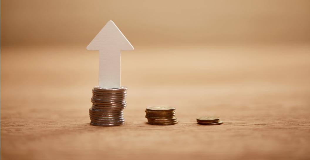 White arrow pointing upwards, standing on a stack of gold coins.