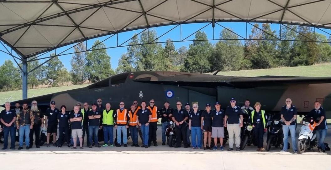 About 40 men and women posing for photo in front of F-111 aircraft.