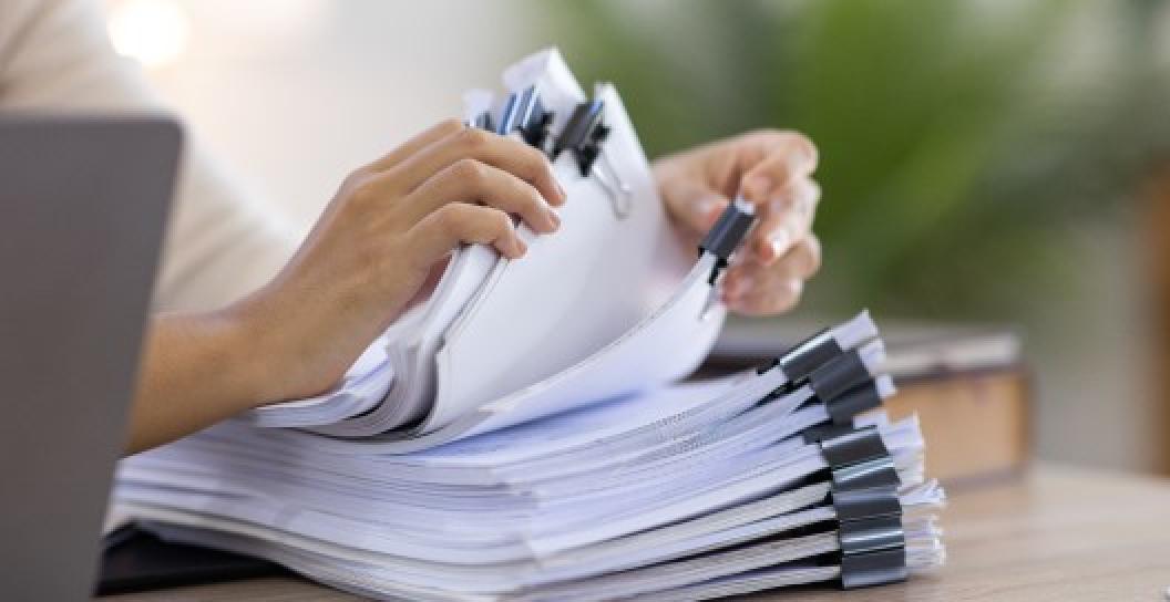 Hands sorting documents on table.