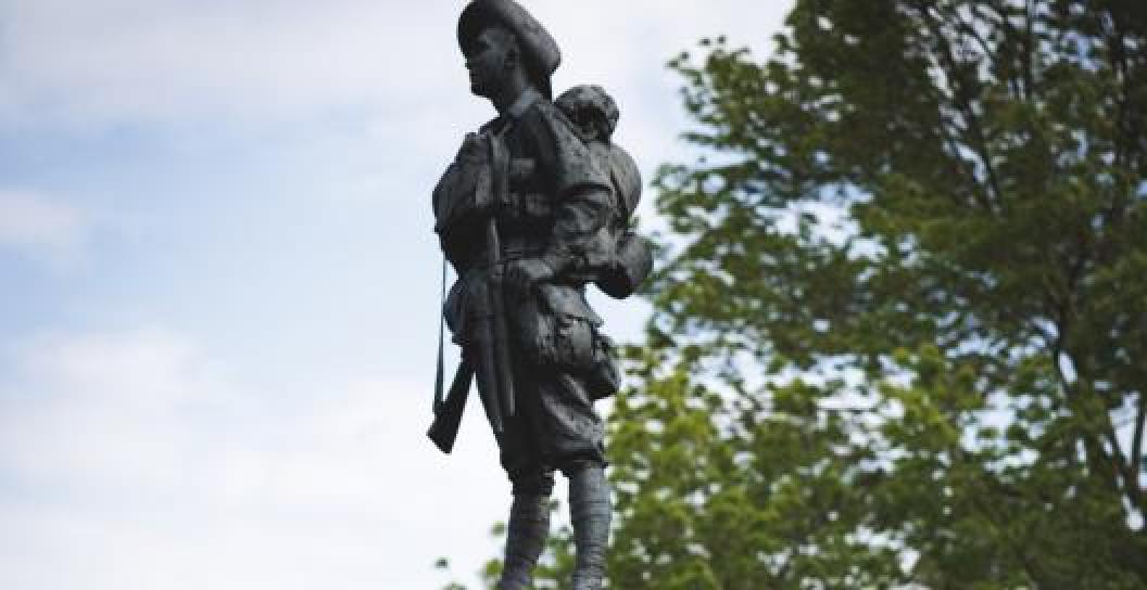 Bronze statue of First World War digger with tree in background