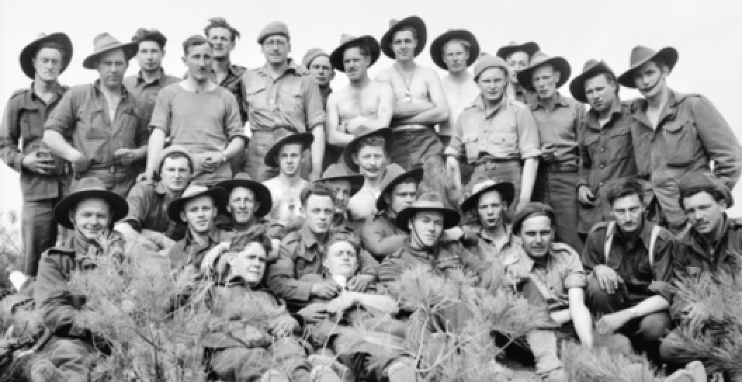 Black and white photo of about 20 soldiers posing for camera