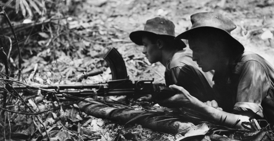 Two young soldiers man a Bren gun in jungle conditions