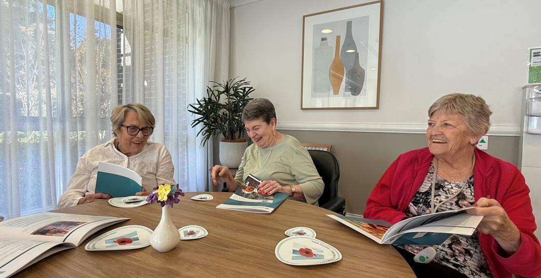 Three ladies looking at DVA's resource, the veteran’s guide to living in an aged care home