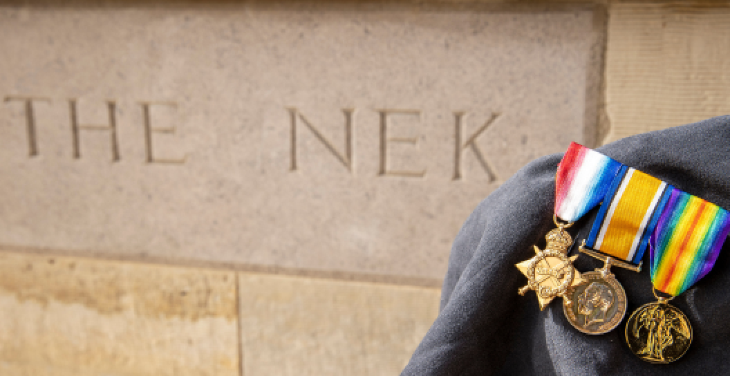 Medals of an Australian Army soldier in front of a memorial to the Charge at the Nek