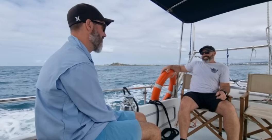 2 men (veterans) sit together on a boat out at sea