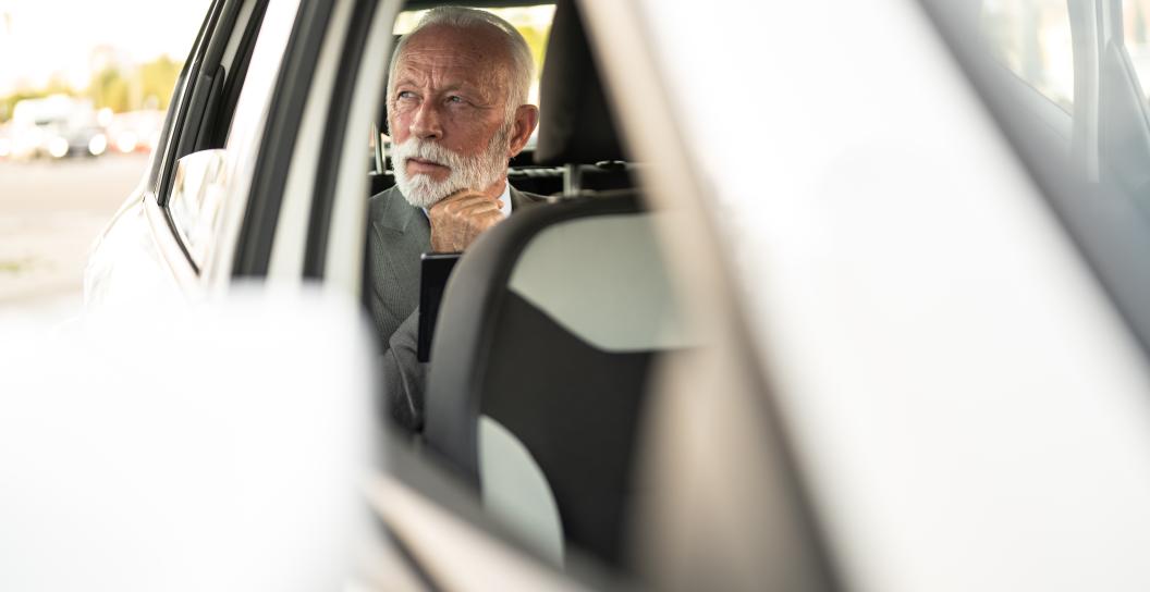 Senior man in back seat of car