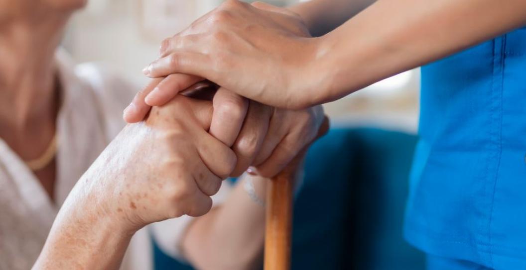 Elderly lady holding hands with carer