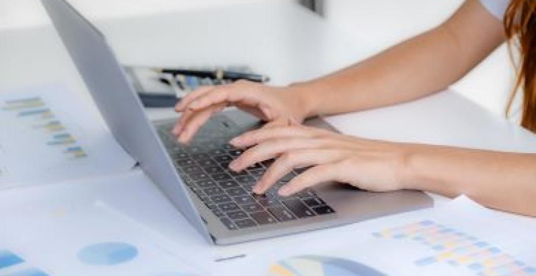 female hand typing on keyboard on a desk in an office