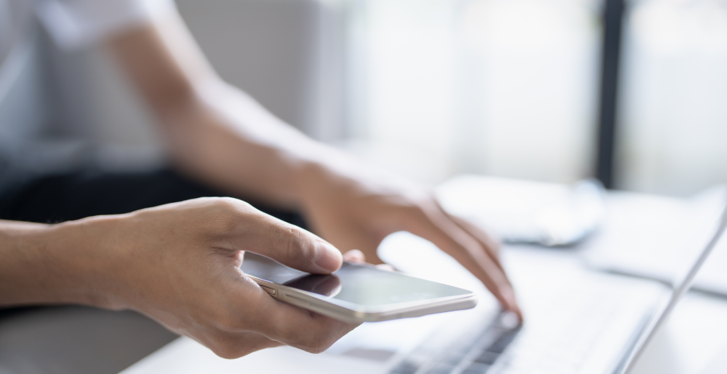Person on computer and holding phone