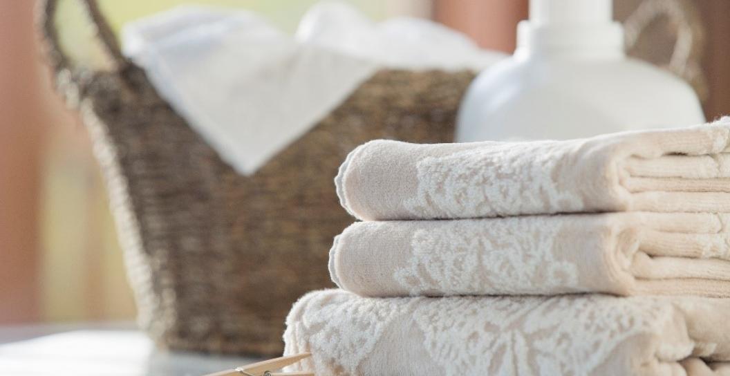 3 stack of folded white towels, next to a washing basket
