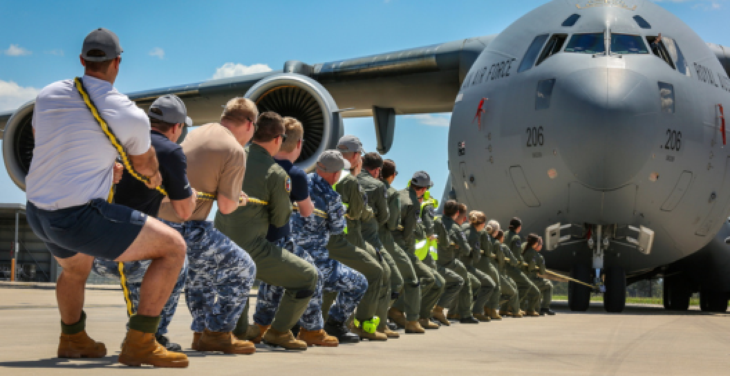 A group of current serving ADF personnel pull a Australian Air Force plane with a rope